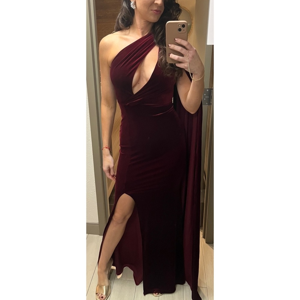 Burgundy velvet gown with asymmetrical cut out and cape sleeve